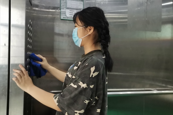 1596425690292078880.jpg 志愿者秦楠给电梯按钮消毒.jpg